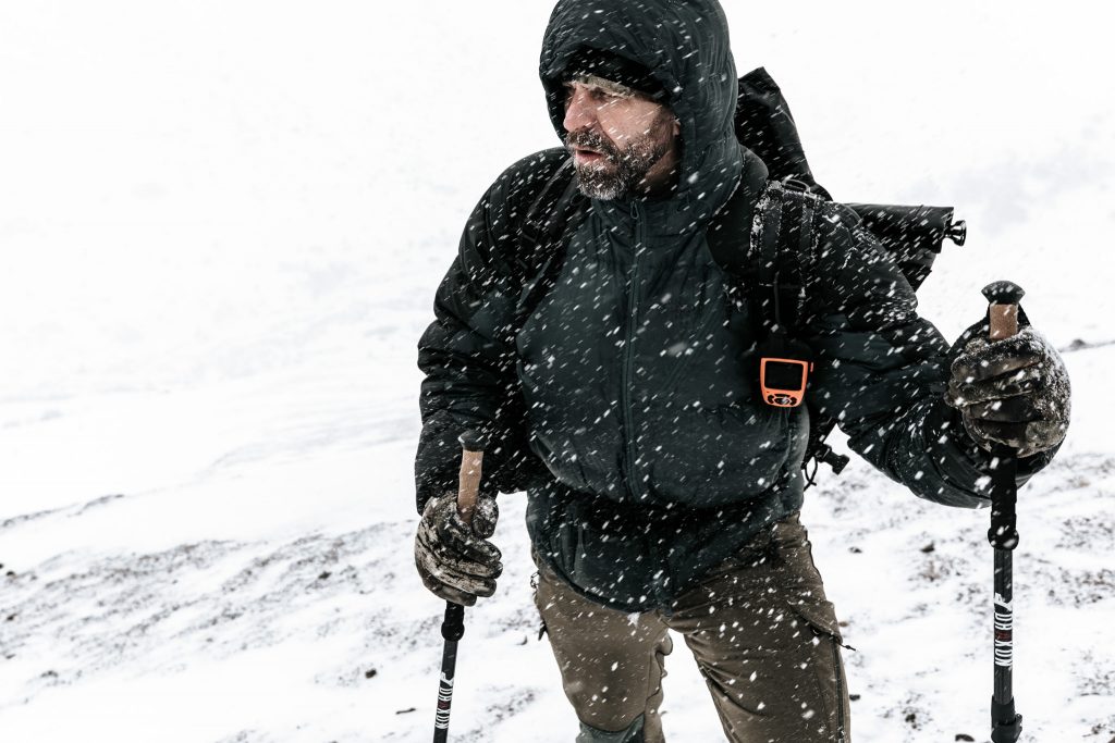 Vaeltaja tarpoo lumisateessa kävelysauvojen kanssa lumen ympäröimänä. Kuva: Joel Forsman